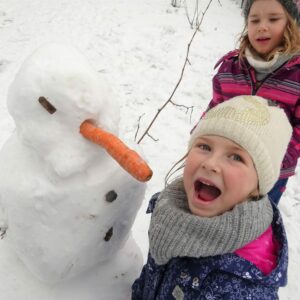 Aktuelles "Wintereinbruch" - Lachendes Kind mit Schneemann und Karotte