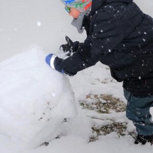 Aktuelles "Wintereinbruch" - Kind beim Schneemann bauen