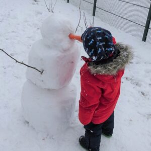 Aktuelles "Wintereinbruch" - Kind beim Schneemann bauen