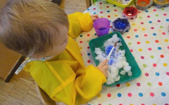 Aktuelles "Malen mit Schnee" - Kind malt mit Pinseln im Schnee