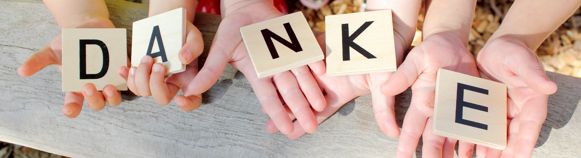 Kinder halten Holzquadrate in den Händen mit dem Wort "Danke"