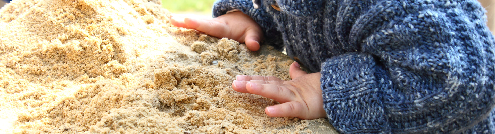 Kleine Kinderhände spielen im Sand