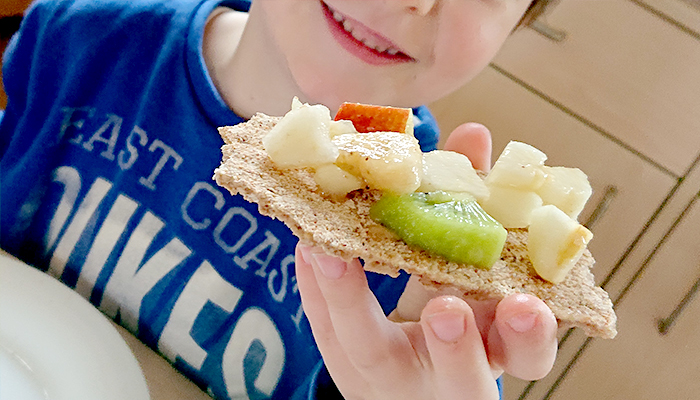 Kind mit Kneckebrot und Obstsalat