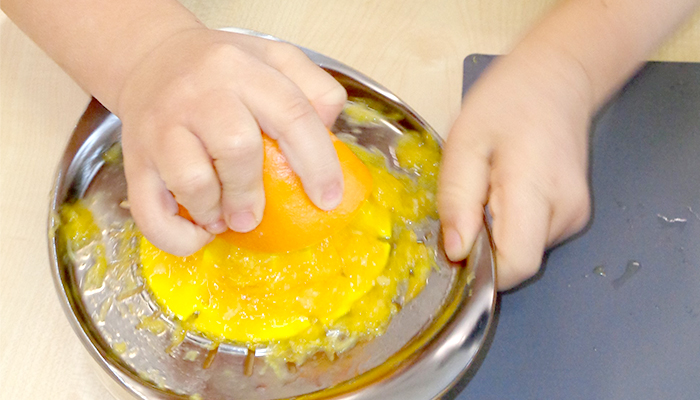 Kind quetscht Saft aus einer Orange