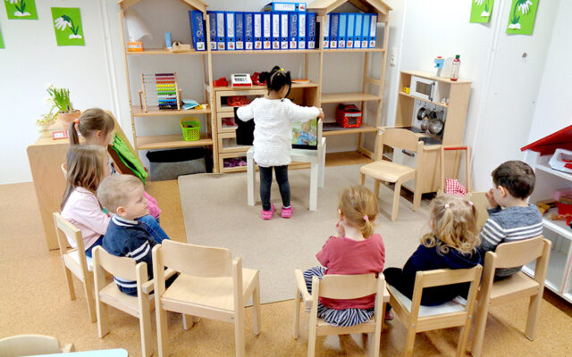 Sitzkreis Kinder mit dem Blick auf das Kamishibai was ein Mädchen aufstellt