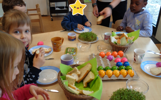 Die Kinder sitzen am Tisch und essen Brot mit Kresse und bunte Ostereier