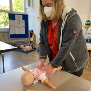 Eine Frau übt die Herzdruckmassage an einer Babypuppe.