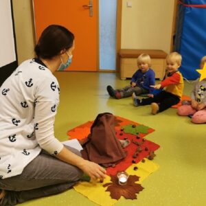 Kinder sitzen auf dem Boden und hören zu.