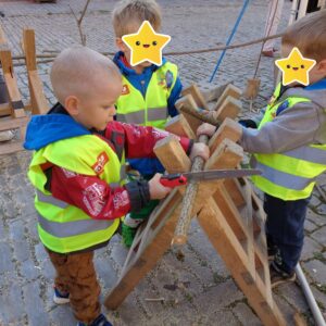 Drei Kinder sägen zusammen ein Stück Holz