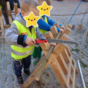 Zwei Kinder sägen ein Stück Holz